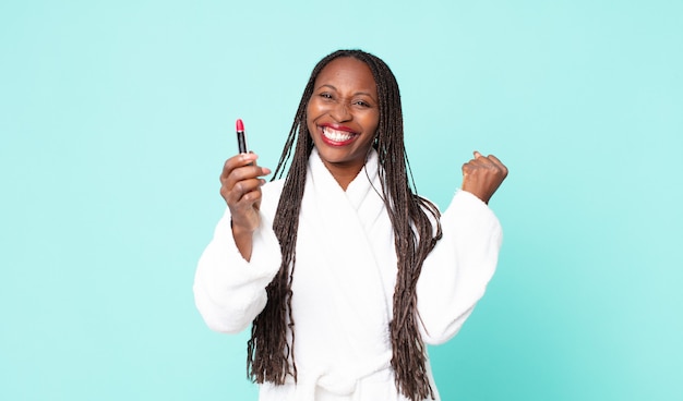 Donna adulta afroamericana nera che indossa accappatoio e tiene un rossetto