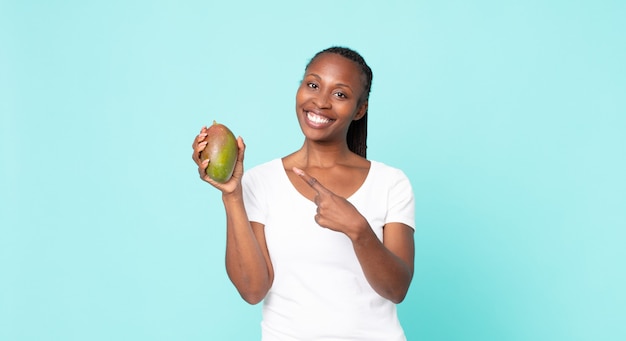 Donna adulta afroamericana nera che tiene un frutto di mango