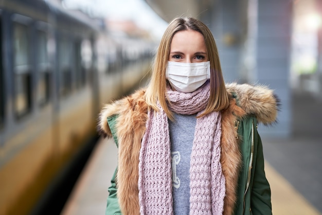 donna adulta alla stazione ferroviaria che indossa maschere a causa delle restrizioni covid-19