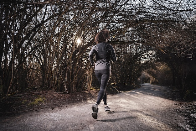 Donna adulta caucasica atletica che corre su un sentiero in una foresta pluviale