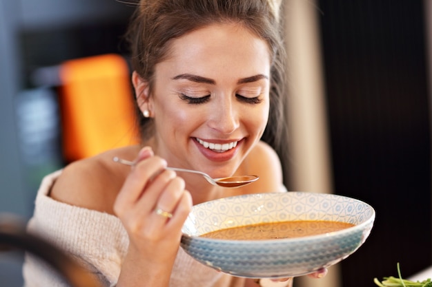 donna adulta che assaggia la zuppa di zucca in cucina