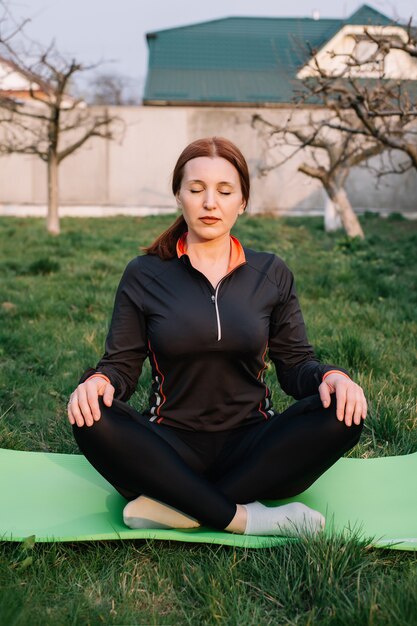 Donna adulta che fa yoga sull'erba