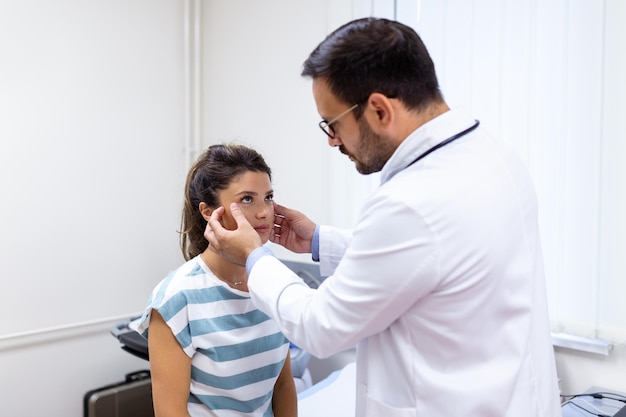 Donna adulta che ha una visita presso l'ufficio dell'oculista Medico che esamina gli occhi della giovane donna in clinica