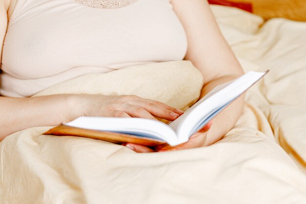 Donna adulta che legge un libro nel letto. Tempo di relax