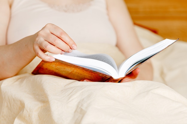 Donna adulta che legge un libro nel letto. Tempo di relax