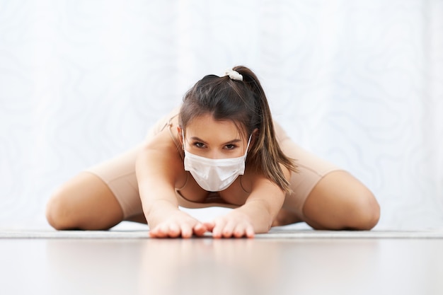 donna adulta che pratica yoga in maschera a casa