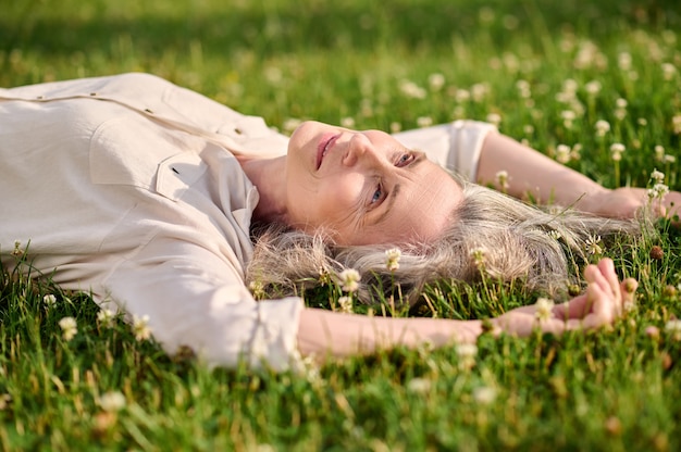 Donna adulta che riposa sull'erba nel parco