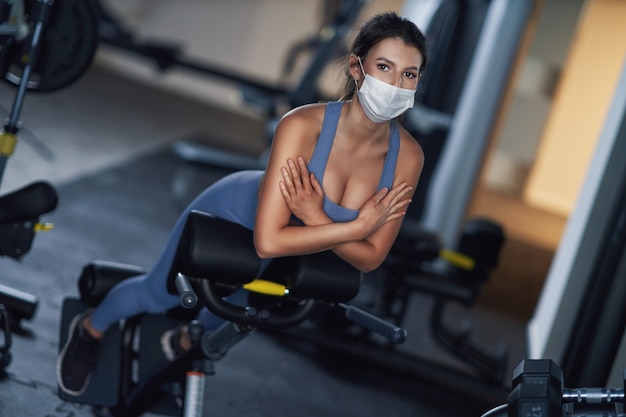 donna adulta che si allena in palestra in maschera a causa del covid-19