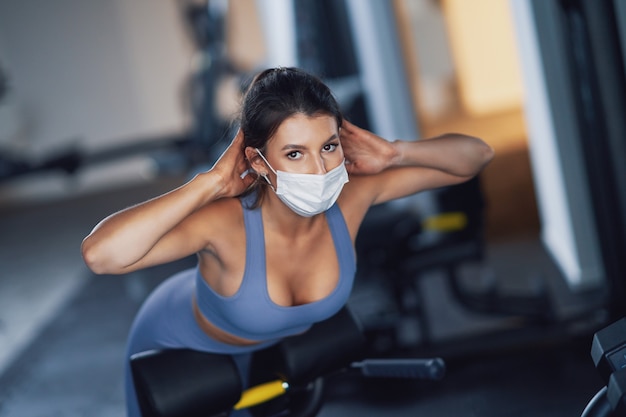 donna adulta che si allena in palestra in maschera a causa del covid-19