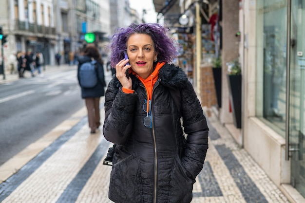 Donna adulta con il telefono Giovane adulto che cammina per strada e usando il suo telefono