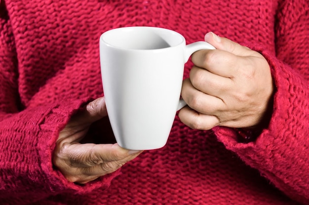 Donna adulta con maglione rosso che tiene una tazza di caffè latte.