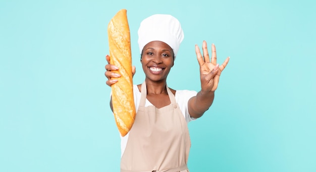 Donna adulta del cuoco unico dell'afroamericano nero che tiene una baguette di pane