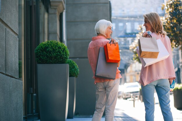 Donna adulta felice amichevole con la madre che trasporta gli acquisti e che cammina. Modello banner