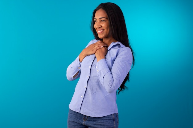 Donna adulta in abbigliamento formale, indossa una camicia blu e jeans in studio fotografico con sfondo blu.