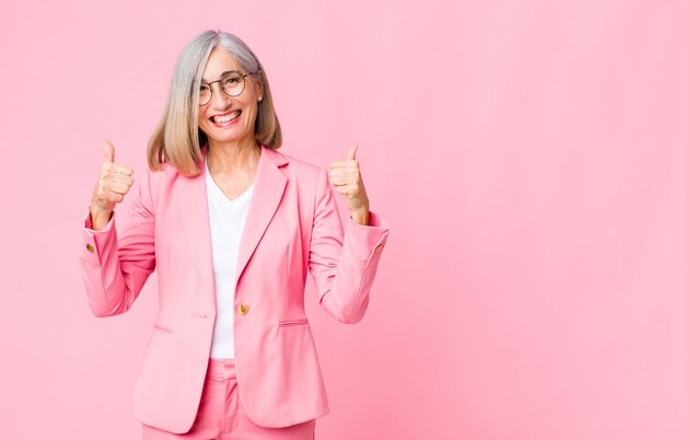 donna adulta in abito rosa positivo e di successo con entrambi i pollici in su