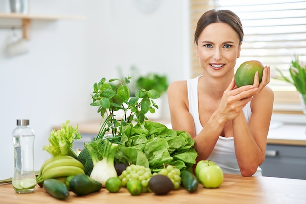 donna adulta in buona salute con cibo verde in cucina