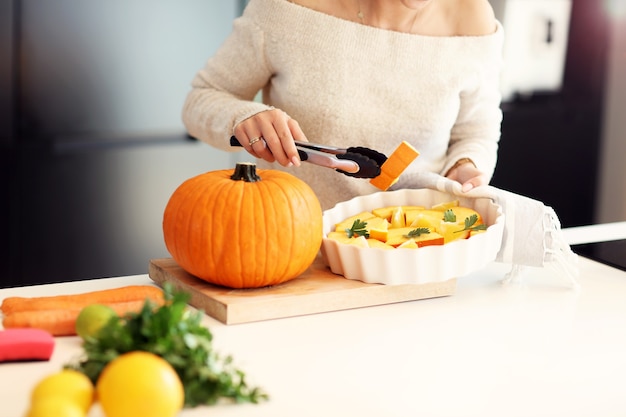 donna adulta in cucina a preparare piatti di zucca per Halloween