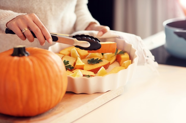 donna adulta in cucina a preparare piatti di zucca per Halloween