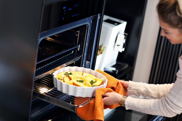 donna adulta in cucina a preparare piatti di zucca per Halloween