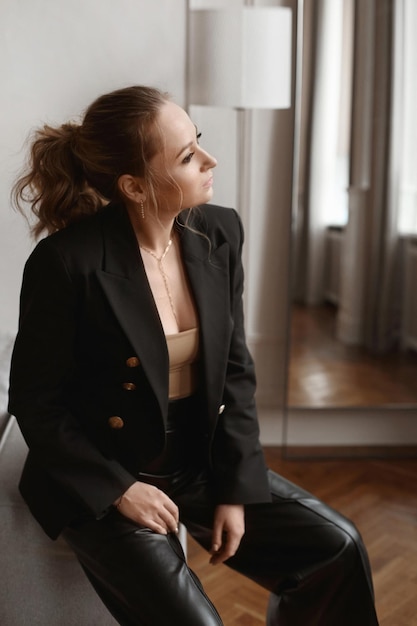 Donna adulta in un blazer nero con trucco delicato in posa al chiuso. Elegante donna alla moda