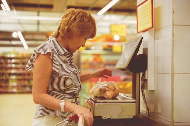 Donna adulta nel negozio di alimentari che fa acquisti di cibo