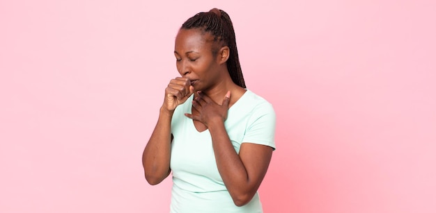 Donna adulta nera afro che si sente male con mal di gola e sintomi influenzali, tosse con la bocca coperta