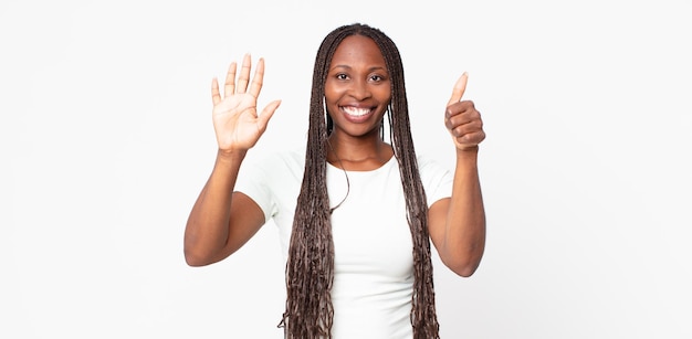 Donna adulta nera afro sorridente e dall'aspetto amichevole, che mostra il numero sei o il sesto con la mano in avanti, conto alla rovescia