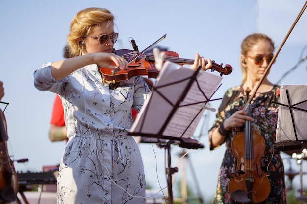 Donna affascinante che suona il violino in orchestra al concerto all'aperto