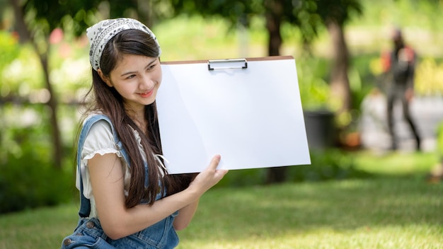 Donna affascinante della ragazza che si siede sul plaid al parco nella soleggiata giornata estiva e usando l'acquerello