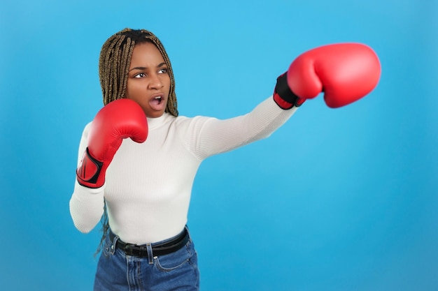 Donna africana aggressiva che indossa guantoni da boxe che lanciano un pugno