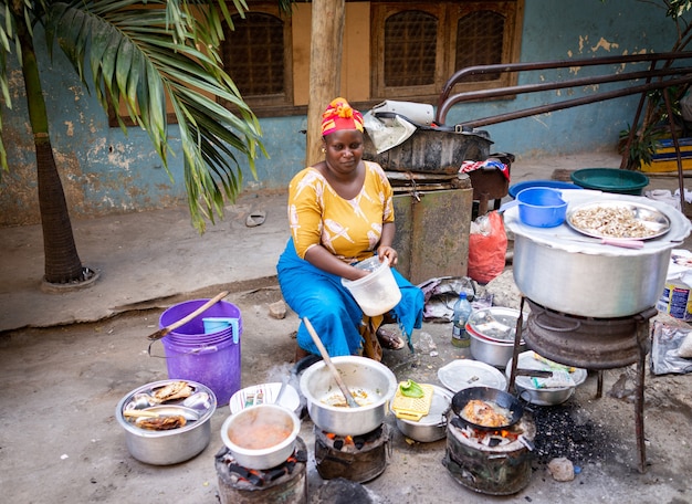 Donna africana che cucina cibo tradizionale in strada