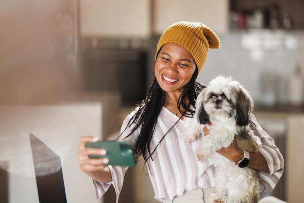 Donna africana che fa selfie e si diverte con il suo cane mentre lavora nel suo ufficio a casa.