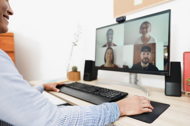 Donna africana che ha videochiamata con i suoi colleghi utilizzando l'app per computer - Focus sulla mano destra