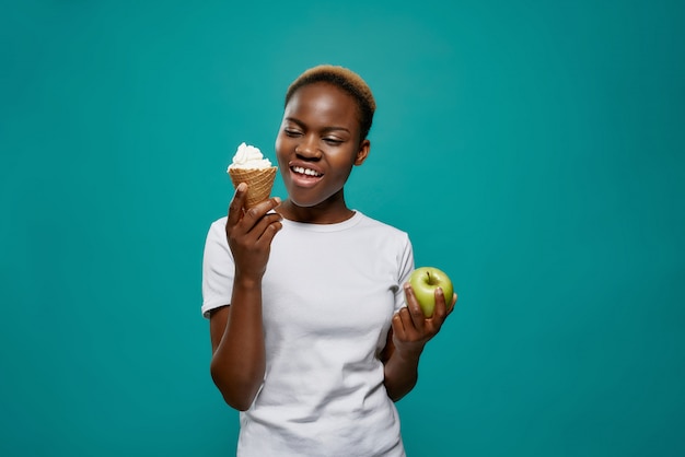 Donna africana che mantiene il gelato saporito e la mela sana