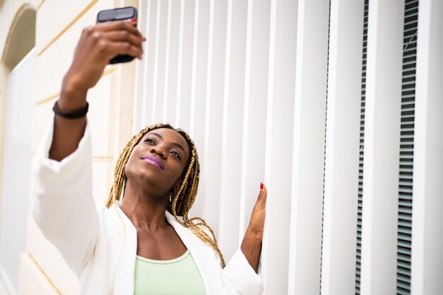 Donna africana che si fa un selfie con un cellulare con un'espressione orgogliosa all'aperto