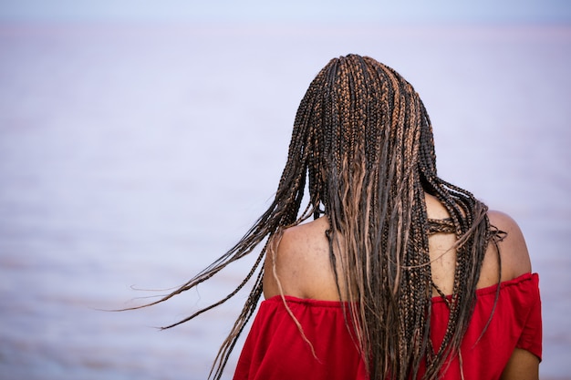 Donna africana con le trecce torna in riva al mare