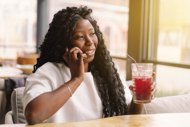 Donna africana utilizzando il telefono nella caffetteria.