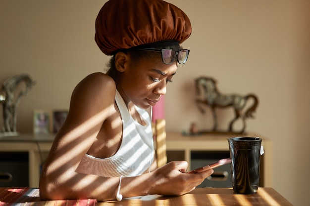 Donna afro-americana che indossa la cuffia per la doccia e utilizzando il cellulare