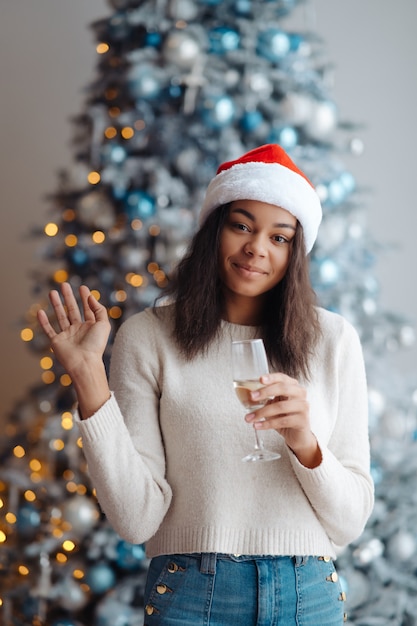 Donna afro-americana con un bicchiere di champagne a casa. Celebrazione di Natale