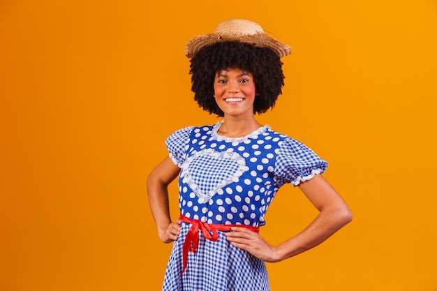 Donna afro brasiliana che indossa abiti tipici per la Festa Junina su giallo