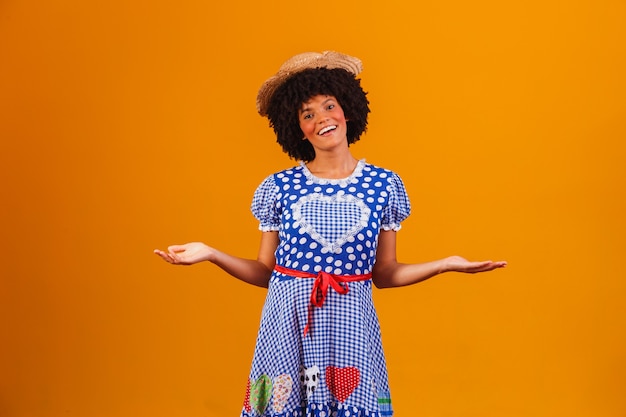 Donna afro brasiliana che indossa abiti tipici per la Festa Junina su giallo