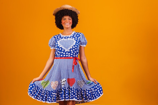 Donna afro brasiliana che indossa abiti tipici per la Festa Junina su giallo