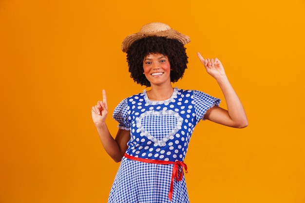 Donna afro brasiliana che indossa abiti tipici per la Festa Junina su giallo