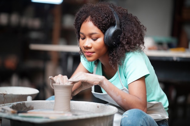 Donna afro che fa la ceramica in officina Modellatura dell'argilla bagnata sul tornio di ceramica