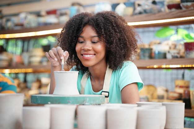 Donna afro che fa la ceramica in officina Modellatura dell'argilla bagnata sul tornio di ceramica