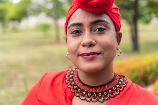 Donna afro che guarda l'obbiettivo con un turbante nel parco