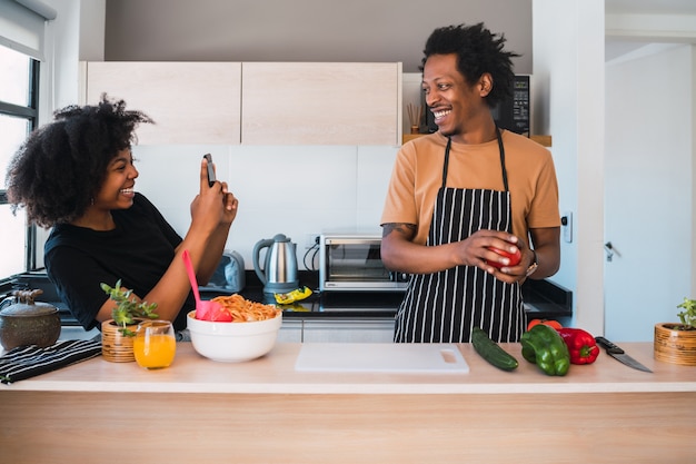 Donna afro che prende foto di suo marito mentre prepara la cena.