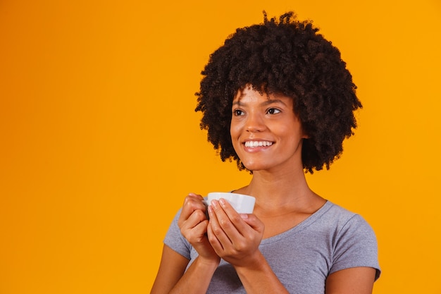 Donna afro che prende il tè sul giallo