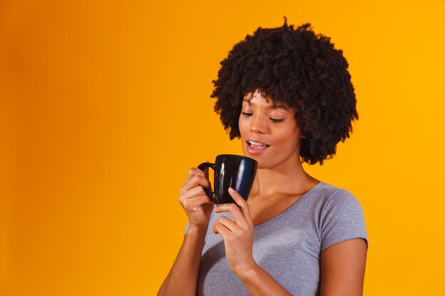 Donna afro che prende il tè sul giallo