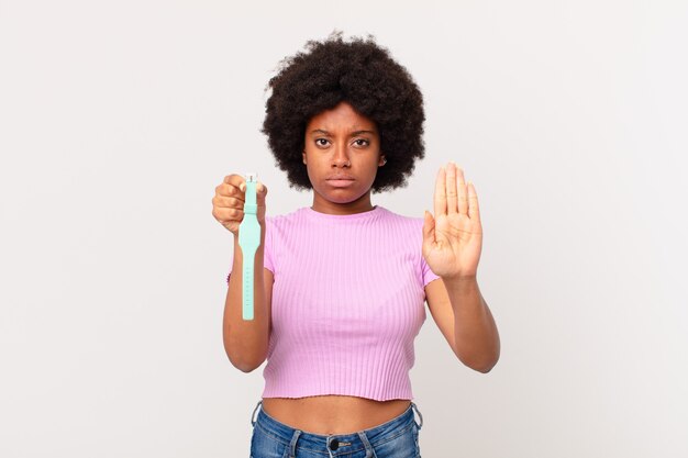 donna afro che sembra seria, severa, dispiaciuta e arrabbiata che mostra il palmo aperto che fa un gesto di arresto concetto di orologio